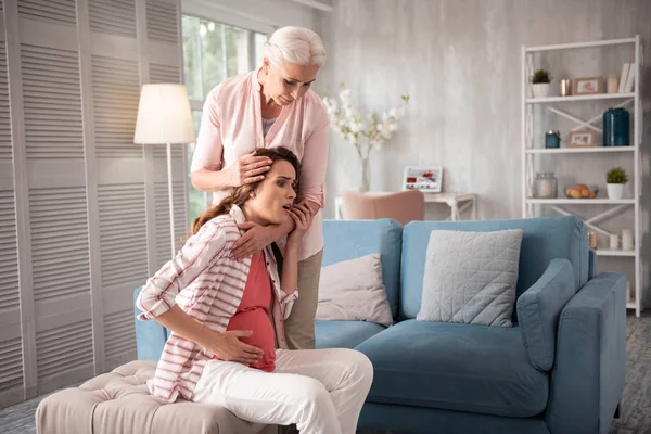 Dark-haired pregnant woman experiencing strong pain