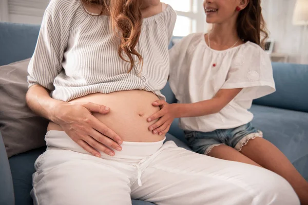 Strahlendes kleines Mädchen legt ihre Hand auf schwangeren Bauch — Stockfoto