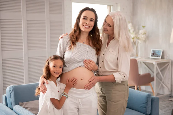 Beaming dark-haired expecting woman spending time with family — Stock Photo, Image