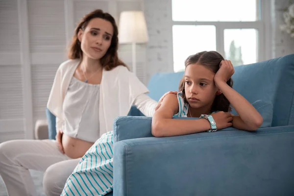 Niña usando reloj de muñeca sentada detrás de su madre embarazada — Foto de Stock