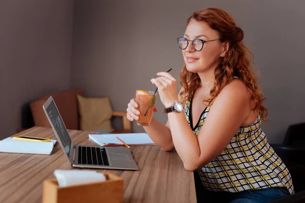 Appealing mature woman wearing glasses drinking cold cocktail