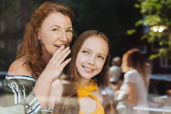 Groen-eyed vrouw stond in de buurt van venster met haar dochter — Stockfoto