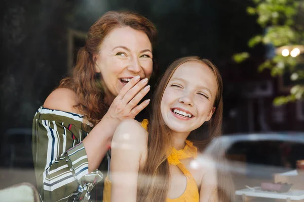 Red-haired woman laughing standing with her daughter