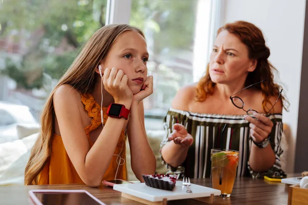 Blonde-haired tiener met behulp van oortelefoons die doen alsof ze niet luisteren — Stockfoto