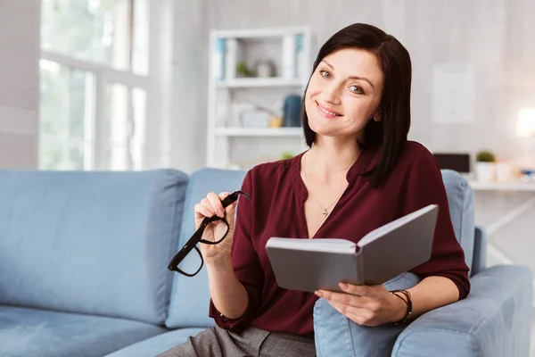Happy woman smiling while sitting with glasses and a notebook — Stock Photo, Image