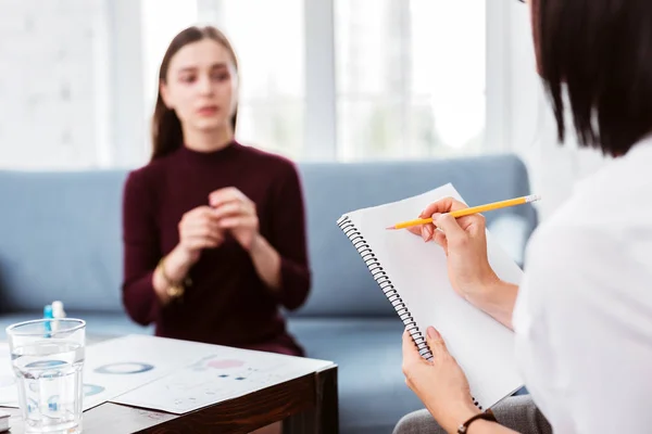 Ruhige Ärztin macht sich Notizen, während ein Patient spricht — Stockfoto