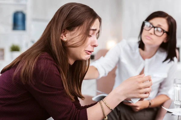 Vriendelijke vrouw aanraken van de schouder van haar patiënt terwijl het zien van haar huilen — Stockfoto