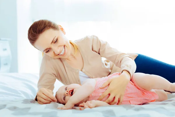 Loira alegre brincando com bebê menina — Fotografia de Stock