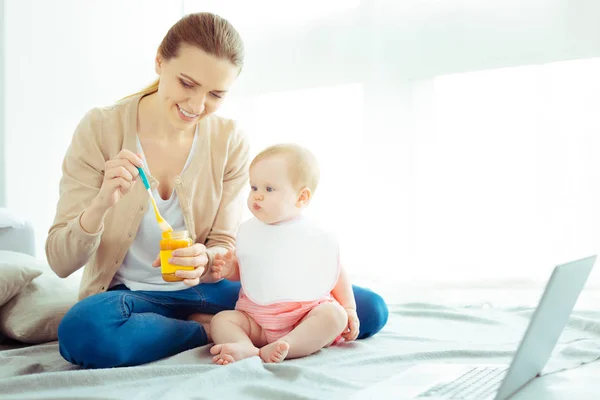 Cheerful young mommy sitting near her baby — Stock Photo, Image