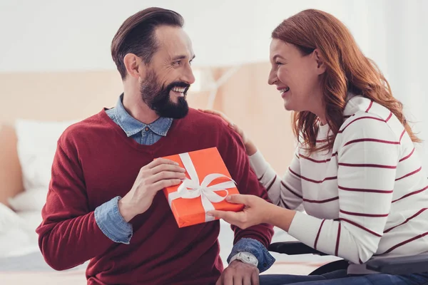 Mujer emotiva riendo mientras le da un regalo a su marido feliz — Foto de Stock