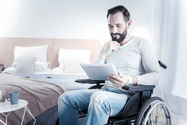 Amable hombre barbudo mirando la pantalla de su gadget — Foto de Stock