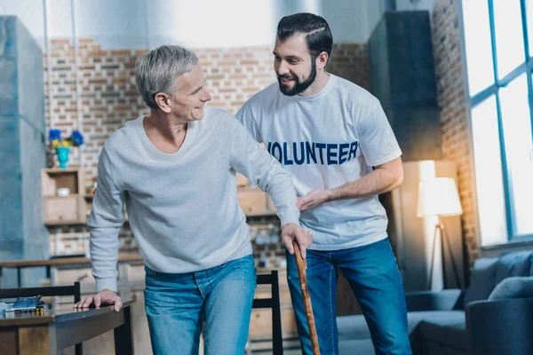 Amable hombre contento ayudando a un hombre anciano —  Fotos de Stock