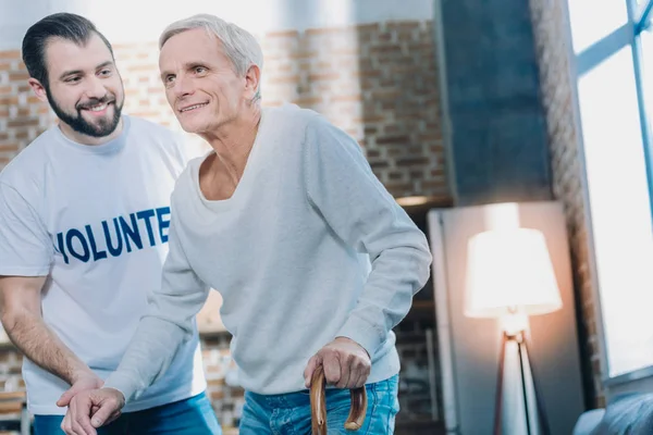 Un hombre amable y exuberante ayudando a un anciano —  Fotos de Stock