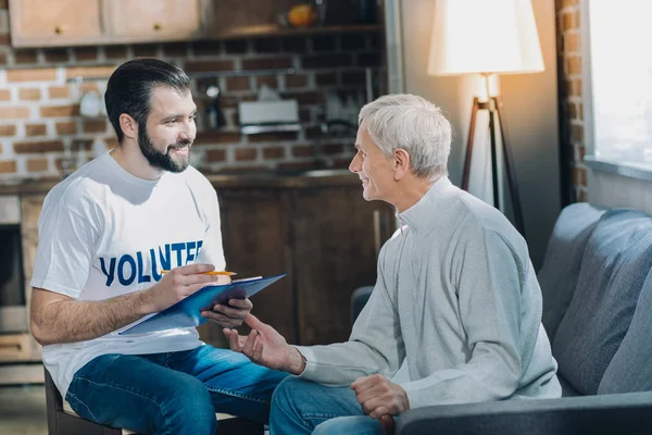 Heureux bénévole parlant avec un vieil homme — Photo
