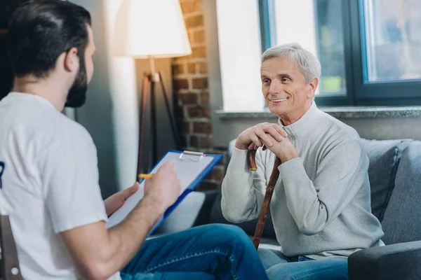 Lachende oude man praten met een vrijwilliger — Stockfoto