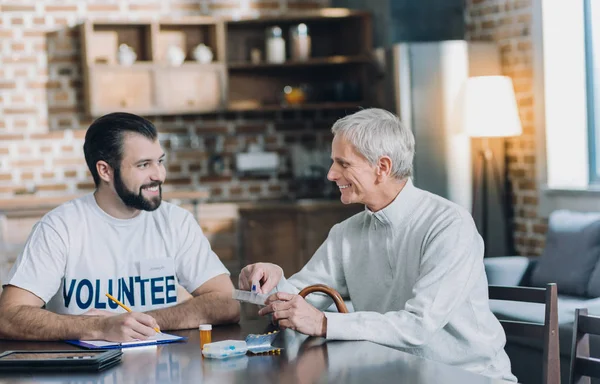 Glad volontär med ett trevligt samtal med en gammal man — Stockfoto