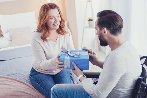 Mujer amable sonriendo mientras saluda a su hermano discapacitado en su cumpleaños —  Fotos de Stock