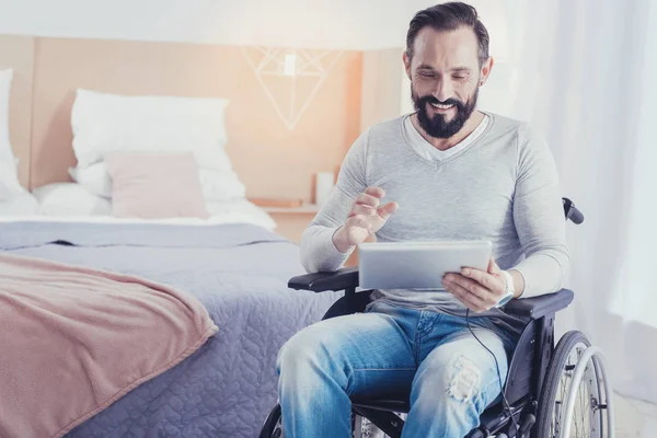 Hombre discapacitado emocional sosteniendo una tableta mientras recibe una videollamada — Foto de Stock