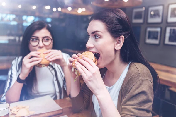 Eszik egy hamburgert vonzó örömmel nő — Stock Fotó