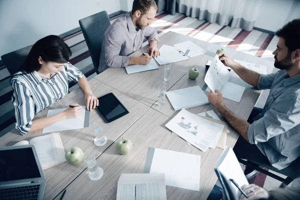 Junge Büroangestellte sitzen an einem großen Tisch — Stockfoto