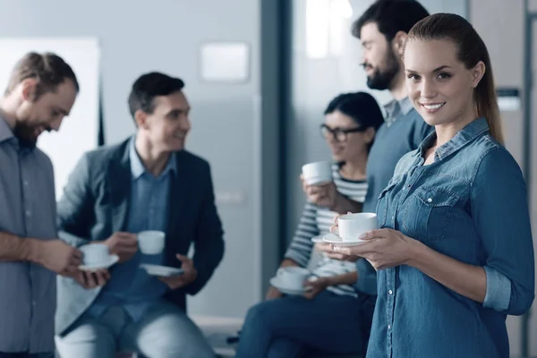 Glada vacker kvinna dricka kaffe med hennes kollegor — Stockfoto