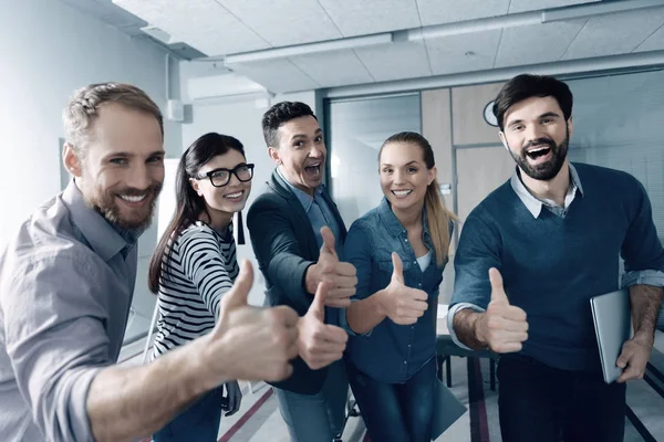 Positive young group of people thumbing up in the office — Stock Photo, Image