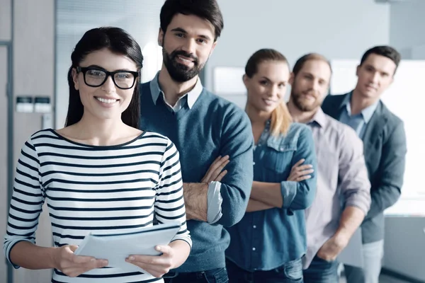 Positiv kvinna och hennes team stående på kontoret — Stockfoto