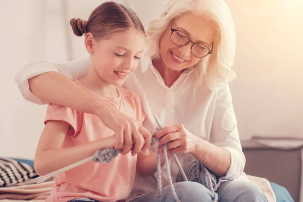 Pensativo senior mujer enseñando nieta tejer —  Fotos de Stock