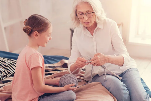Thoughtful retired woman imparting her knowledge of knitting — Stock Photo, Image