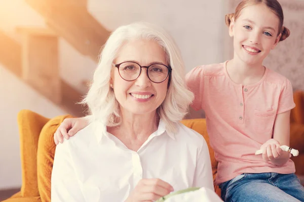 Glad preteen flicka kramar hennes leende mormor — Stockfoto