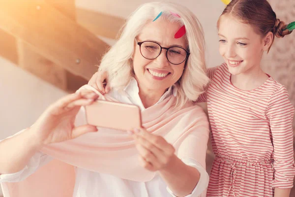 Alegre abuela y niña tomando selfies en el interior —  Fotos de Stock