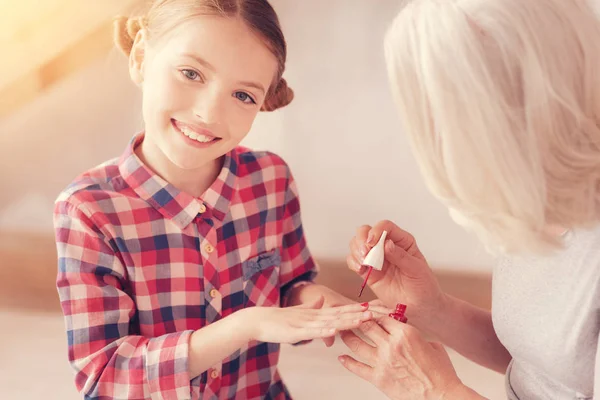Mindful grandmother painting nails of her stylish granddaughter — Stock Photo, Image