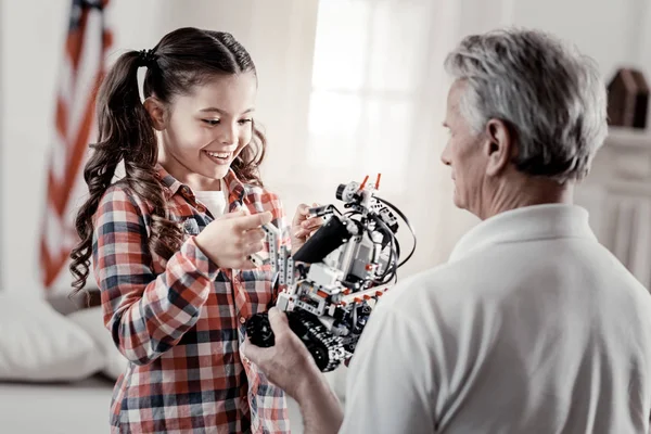 Happy fascinated beautiful girl touching robot toy