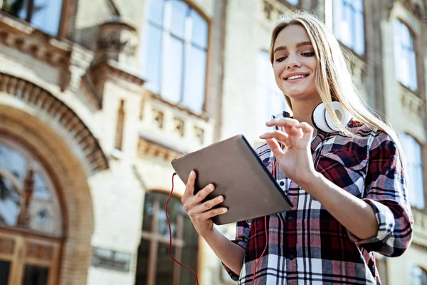 Porträtt av leende blondin att titta på hennes gadget — Stockfoto