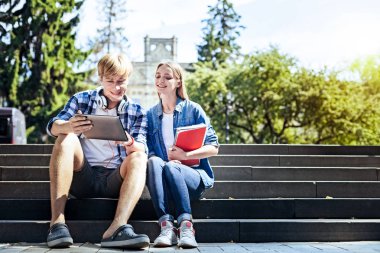 Açık havada oturma ve touchpad üzerinde çalışma neşeli öğrenciler