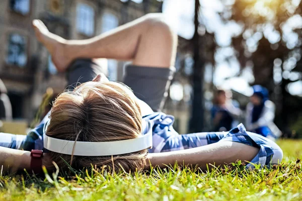 Расслабленный парень лежит на траве, наслаждаясь музыкой — стоковое фото