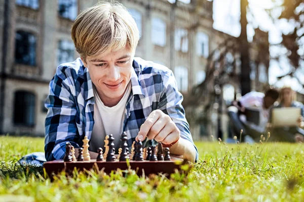 Handsome young man playing chess outdoors