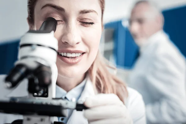 Retrato de una científica positiva mirando al microscopio —  Fotos de Stock