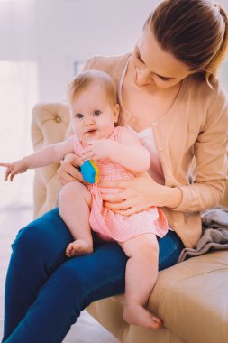 Annesi dizlerinin üstüne oturan ve memnun seyir tatlı yürümeye başlayan çocuk