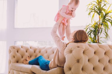 Annesi onu havaya kaldırmış süre gülümseyen şirin bebek