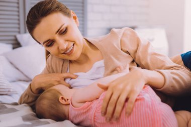 Kadın emzirme bebeğin gülümseyen ve memnun seyir