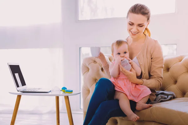 Smiling woman giving water to her child while being at home — Stock Photo, Image