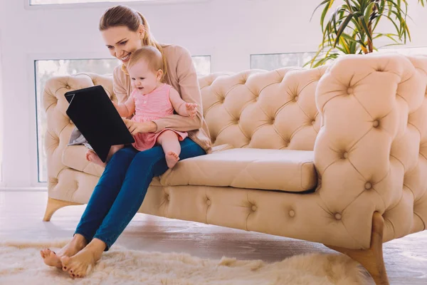 Positive mother smiling while showing cartoons to her baby — Stock Photo, Image