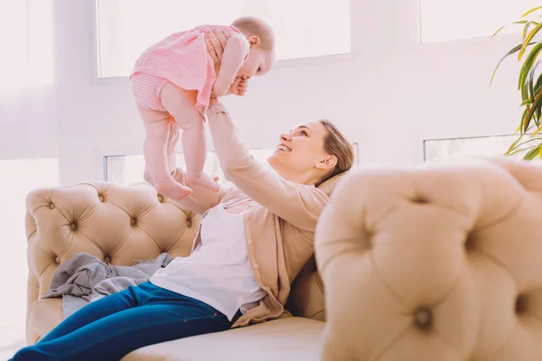 Smiling mother playing with her daughter and putting her up — Stock Photo, Image
