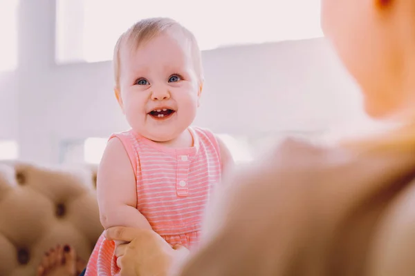 Bebé positivo sonriendo mientras está sentado en las rodillas de una madre — Foto de Stock