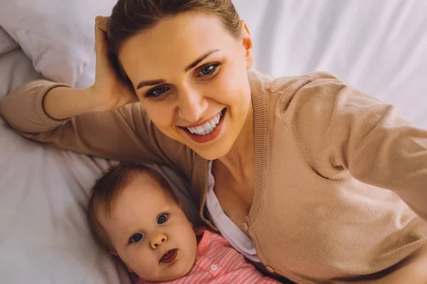 Hermosa mujer mirando feliz mientras toma selfie con su hija bebé — Foto de Stock