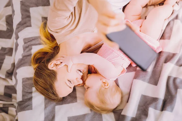 Lovely baby touching the face of a laughing mother and looking calm — Stock Photo, Image