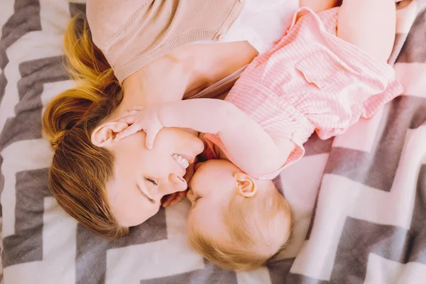 Cute baby girl kissing her mother while touching her face — Stock Photo, Image