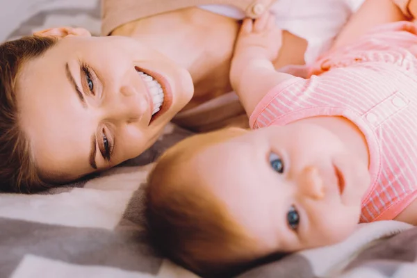 Mujer emocional sonriendo felizmente mientras mira a su lindo bebé —  Fotos de Stock
