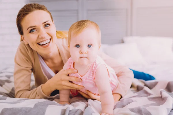 Determined baby trying to crawl and a kind mother helping her — Stock Photo, Image